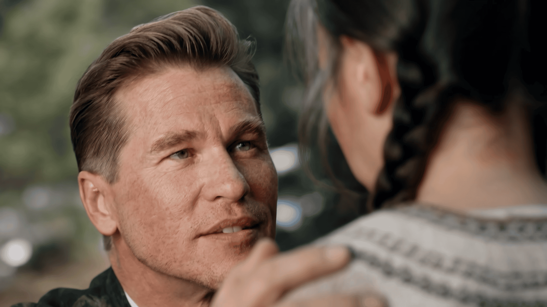 Val Kilmer olhando para uma menina, que está de costas