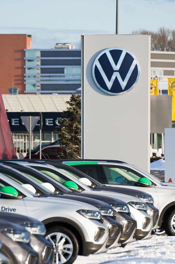 Logo da Volkswagen na fachada de um prédio ao lado de vários veículos