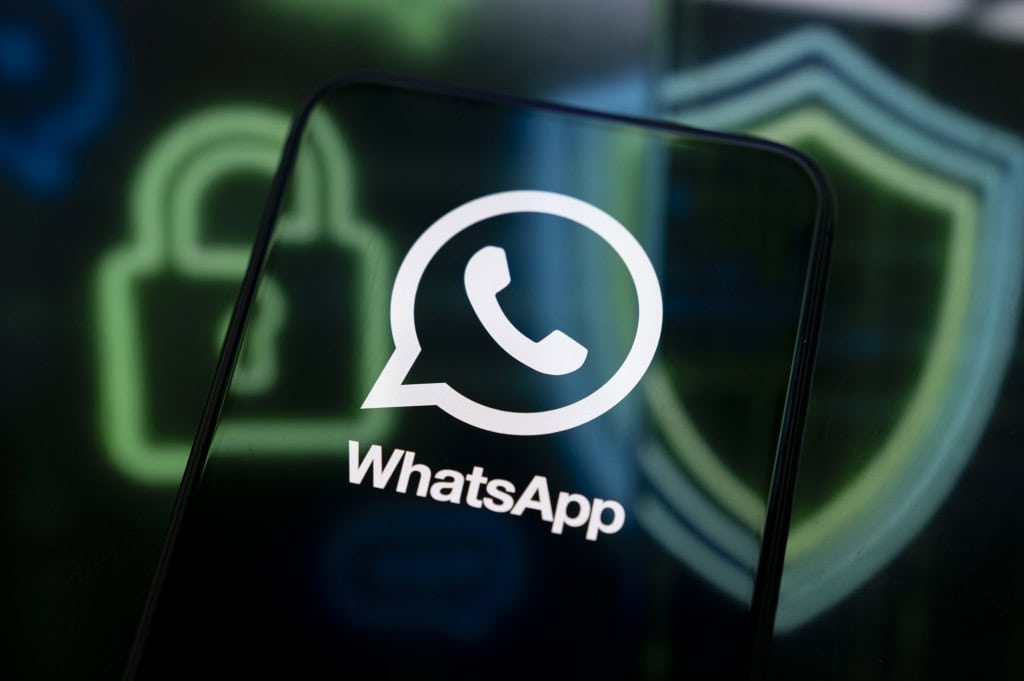 Logo do WhatsApp exibido na tela de um smartphone, com ícones de cadeado e escudo desfocados ao fundo
