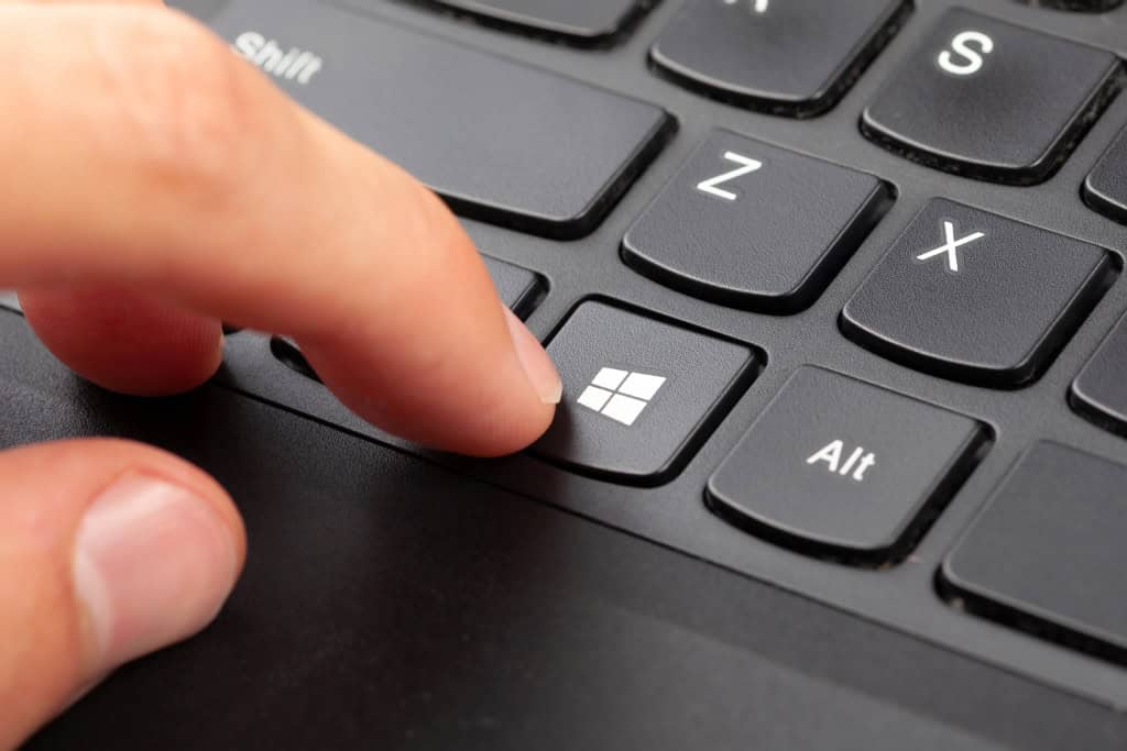 Dedo de uma pessoa apertando o botão do Windows em um teclado