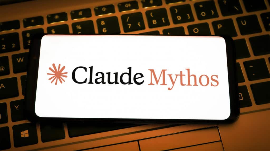 Celular com logomarca do Claude Mythos na tela colocado em cima de teclado de notebook