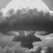 Foto de explosão de bomba nuclear; explosão e fumaça projetam forma de cogumelo no horizonte