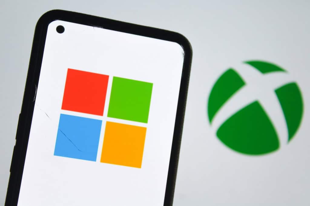 Logotipo da Microsoft exibido em smartphone com símbolo do Xbox ao fundo