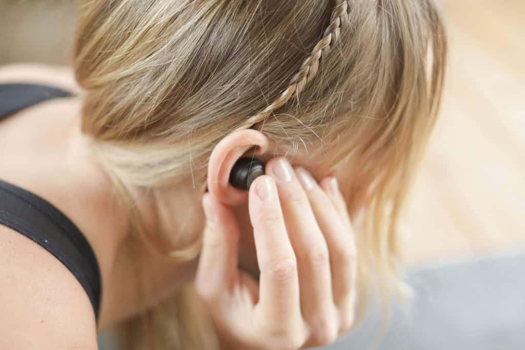 Mulher ouvindo música na academia pelo fone de ouvido