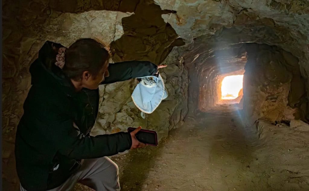 Arqueóloga apontando para a saída do túnel