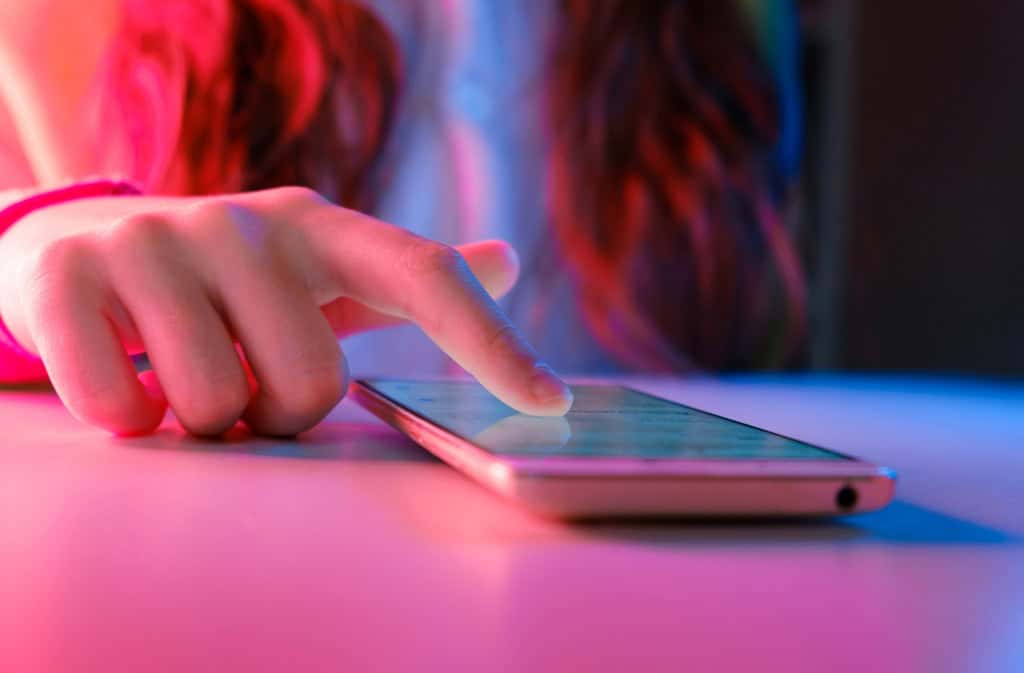 adolescente tocando na tela de um smartphone