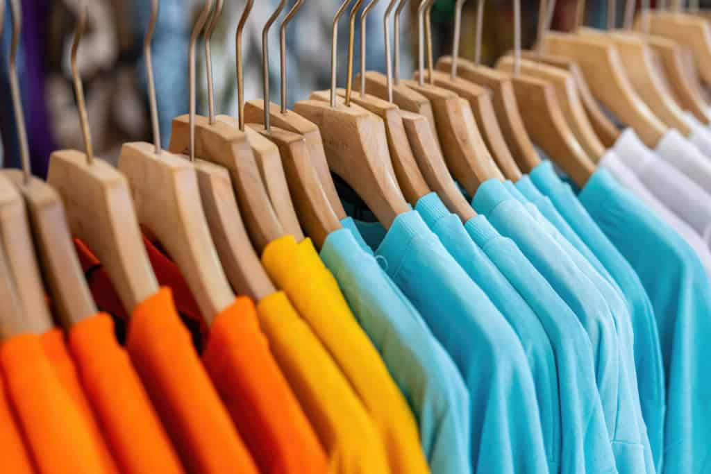 Arara com blusas coloridas penduradas em cabides, imagem associada ao termo popular 
