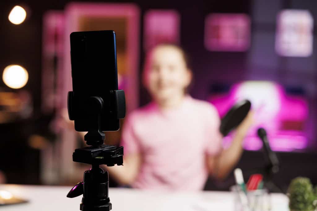 Close up da câmera profissional do smartphone de gravação usada pela estrela da internet da geração Z para fazer livestream