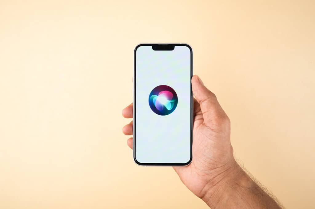 mão segura um iphone com o símbolo da siri ao centro