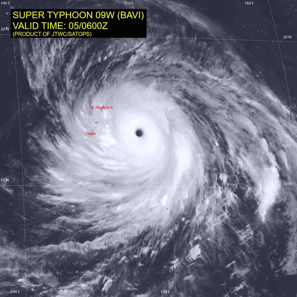 Imagem de satélite mostra o supertufão Bavi no oceano Pacífico, com um olho bem definido e extensas faixas de nuvens em espiral. O mapa identifica Guam e as Ilhas Marianas do Norte, próximas da trajetória da tempestade.