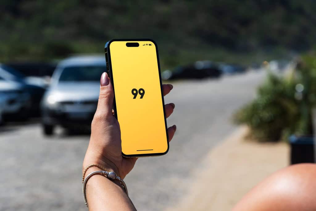 Logo da 99 em um smartphone na mão de uma pessoa