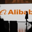 Logo da Alibaba com pessoas passando em frente