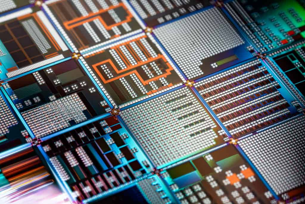 Macrofotografia em ângulo inclinado dos circuitos microscópicos e blocos lógicos gravados na superfície de um wafer de semicondutor.