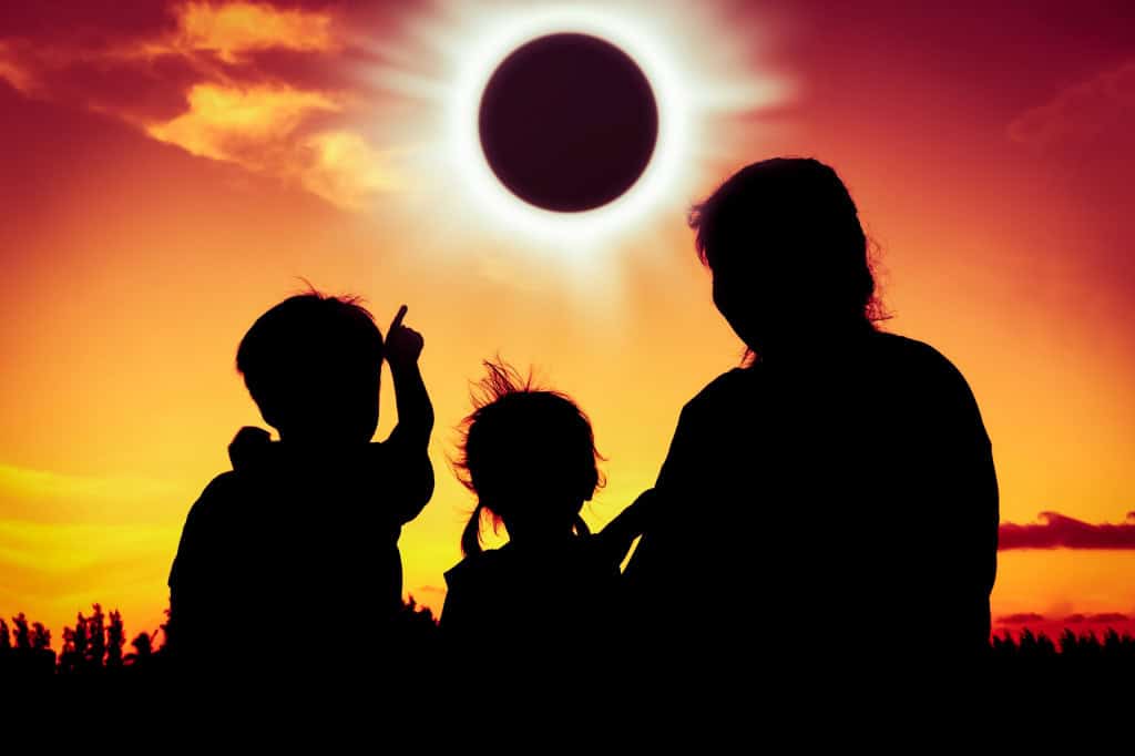Silhuteas de pessoas observando um eclipse