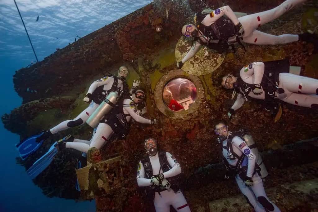 Mergulhadores posando para uma foto em torno do habitat submarino