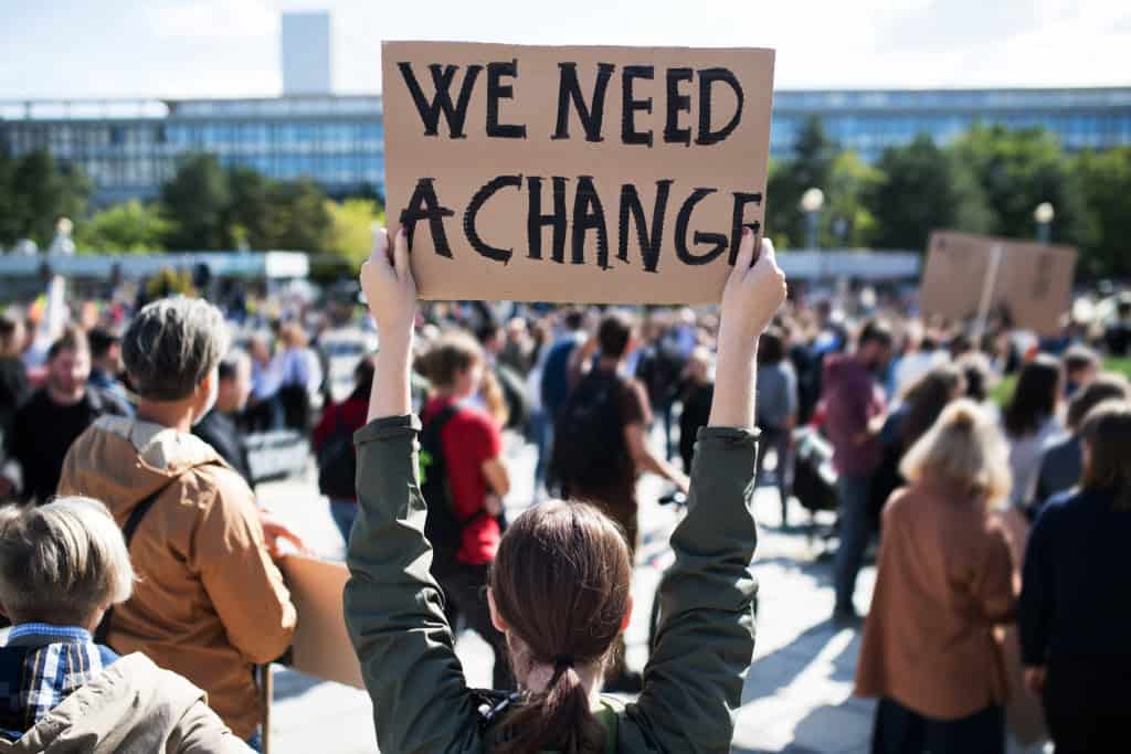mulher segurando um cartaz pedindo mudanças em manifestação