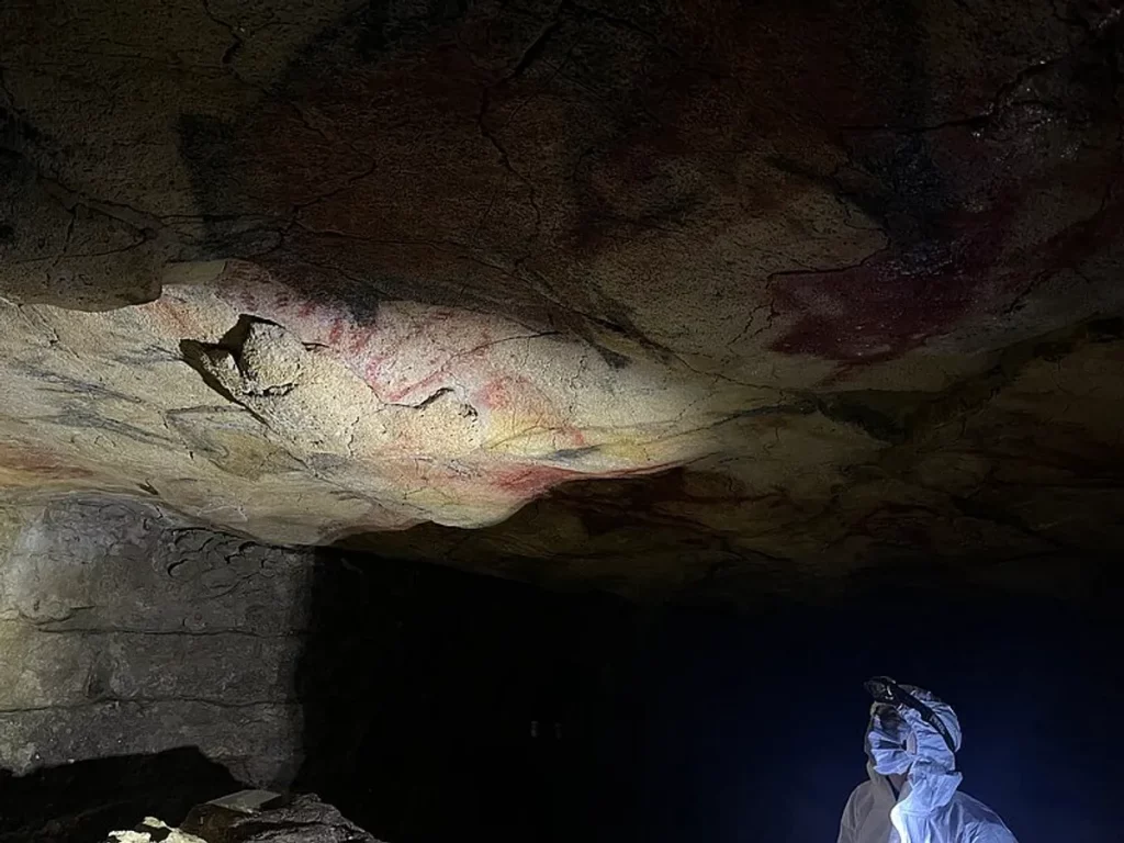 Pesquisador observando pinturas rupestres em caverna na Península Ibérica.