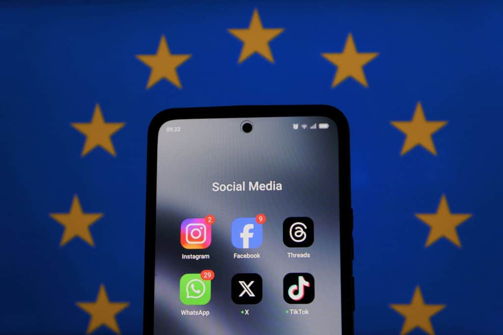 Celular com redes sociais com a bandeira da União Europeia de fundo