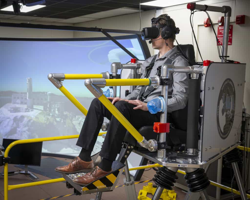 Matt Kamlet, funcionário do Centro de Pesquisa de Voo Armstrong da NASA em Edwards, Califórnia, está sentado no simulador de realidade virtual de qualidade de viagem para passageiros durante um estudo sobre o movimento de táxis aéreos