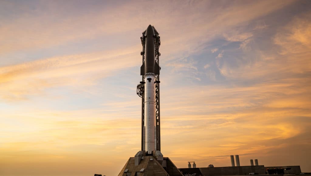 Pôr do sol em Starbase com uma Starship totalmente empilhada.