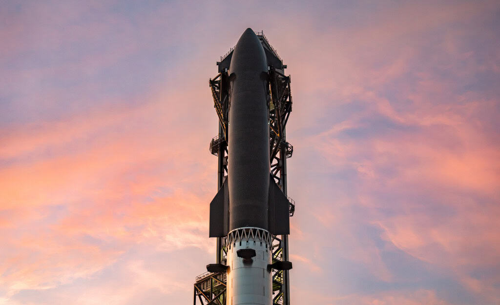 Pôr do sol em Starbase com uma Starship totalmente empilhada.
