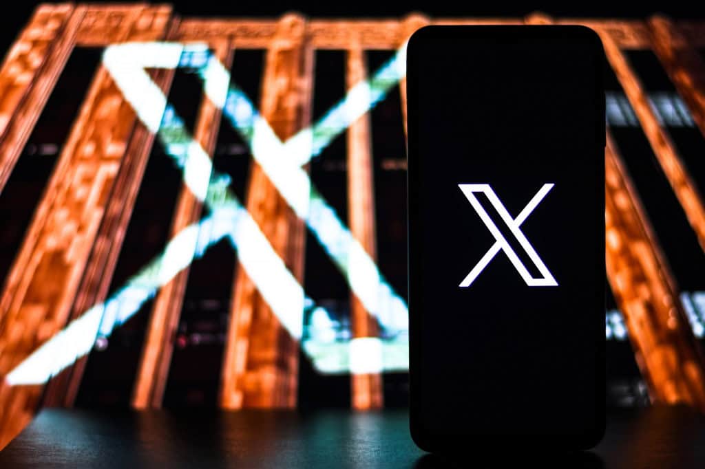 Logo do X em um smartphone e projetado em uma construção