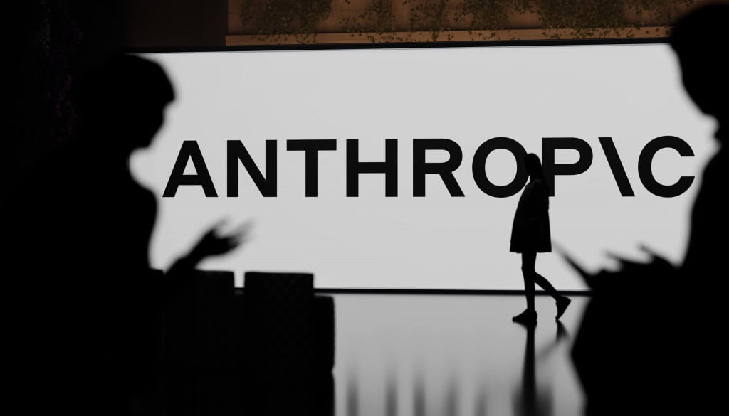 Logo da Anthropic em uma parede com pessoas ao redor