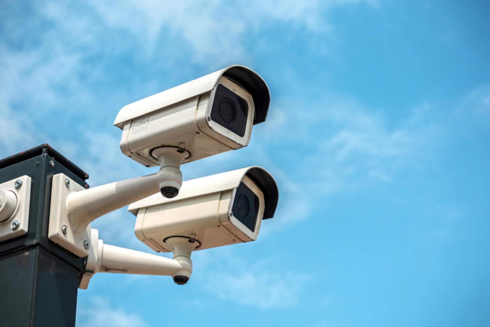 Duas câmeras de segurança instaladas em uma estrutura externa, apontadas para diferentes direções.