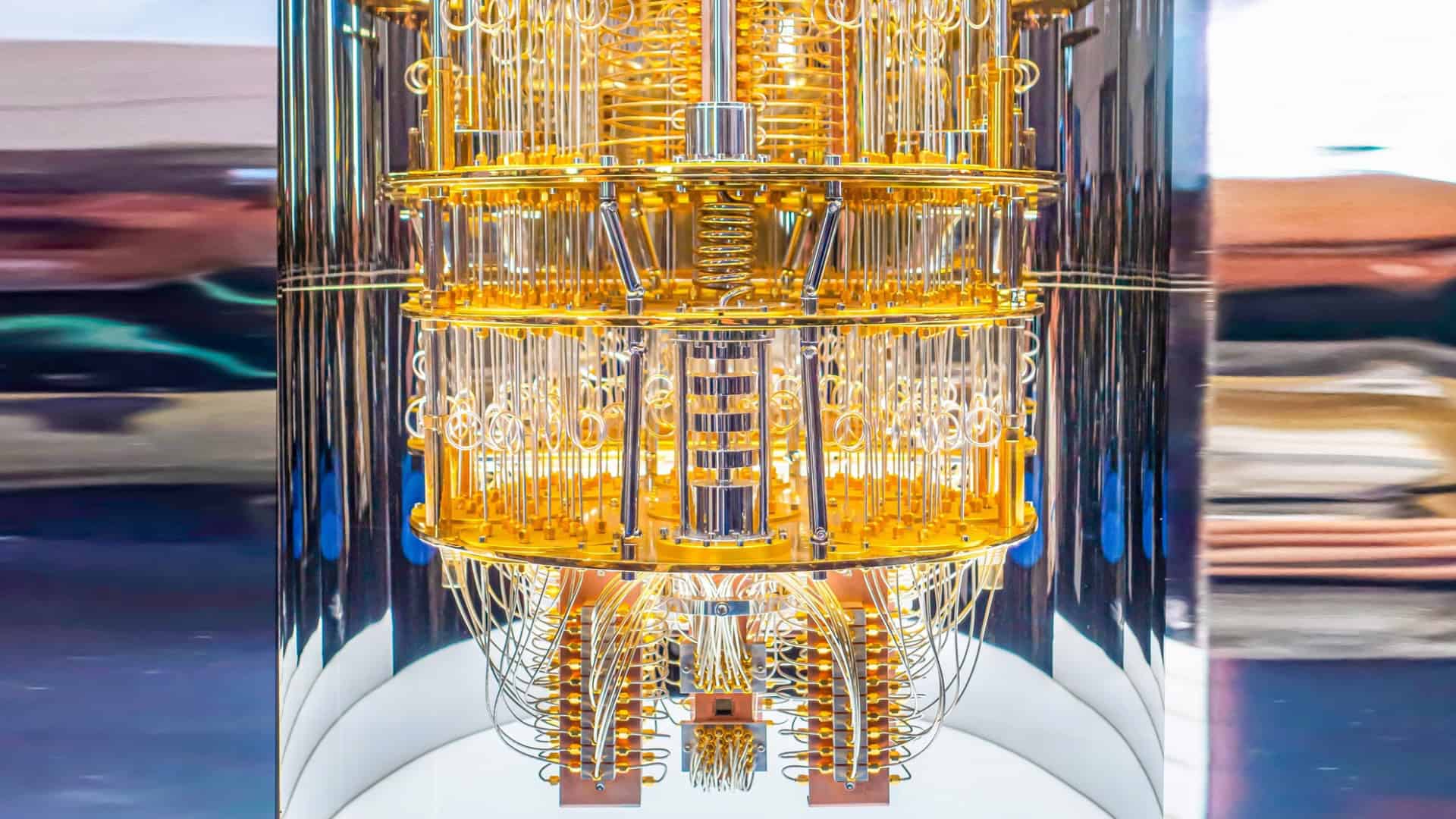 Computador quântico IBM Q System One com estrutura metálica dourada e cabos internos expostos.