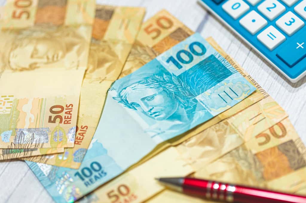 Notas de real sobre uma mesa, acompanhadas de uma calculadora e uma caneta, representando o planejamento financeiro de uma empresa.