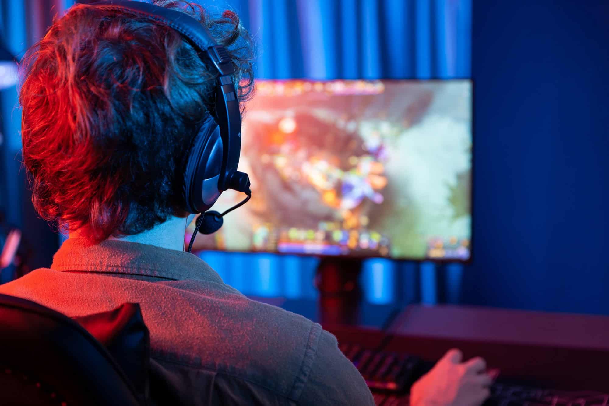 Pessoa joga videogame em um computador usando fones de ouvido.
