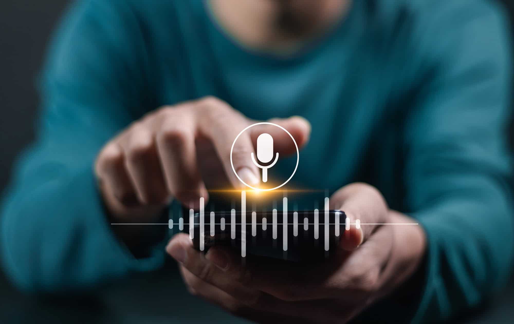 Pessoa segura um celular com ícone de microfone e ondas sonoras representando análise de voz por inteligência artificial.