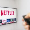 Pessoa usando um controle remoto para acessar o Netflix em uma TV.
