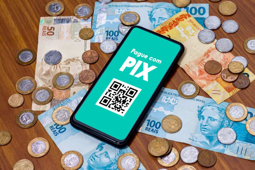 Pix na tela do smartphone com várias moedas ao redor.
