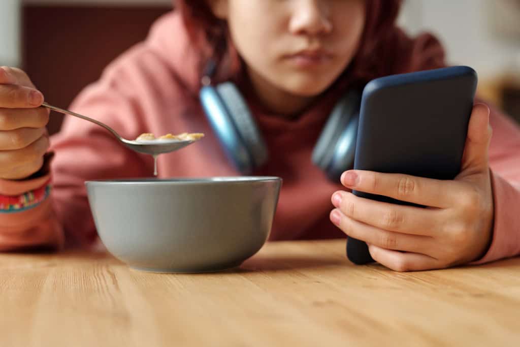 Adolescente usando um celular na mesa de café