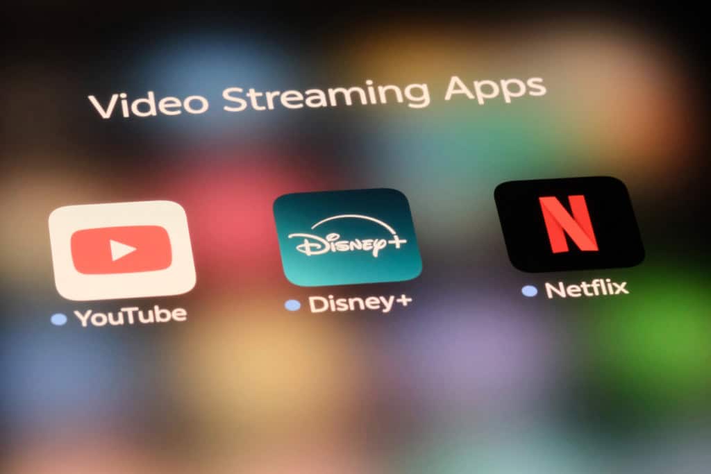 Logos do Youtube, Disney+ e Netflix na tela de um celular