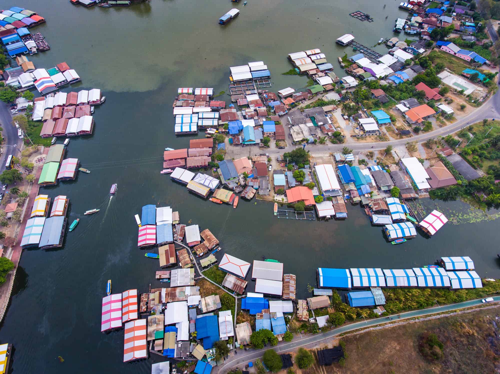 Vista aérea de uma área urbana construída às margens de um rio, com casas, comércios e estruturas sobre a água