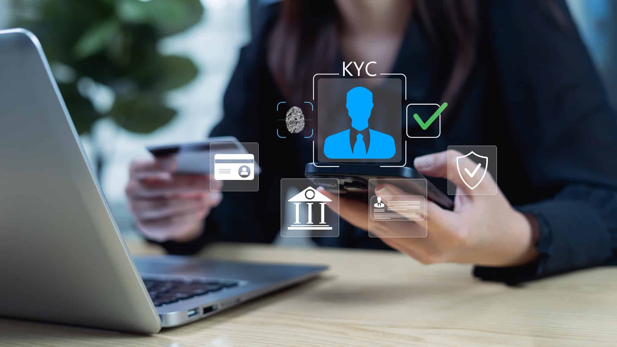 Pessoa usando smartphone e cartão diante de um notebook, com elementos gráficos de identificação, biometria, segurança e KYC sobrepostos à imagem.