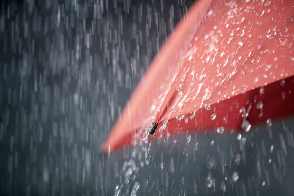Guarda-chuva vermelho sob chuva intensa.