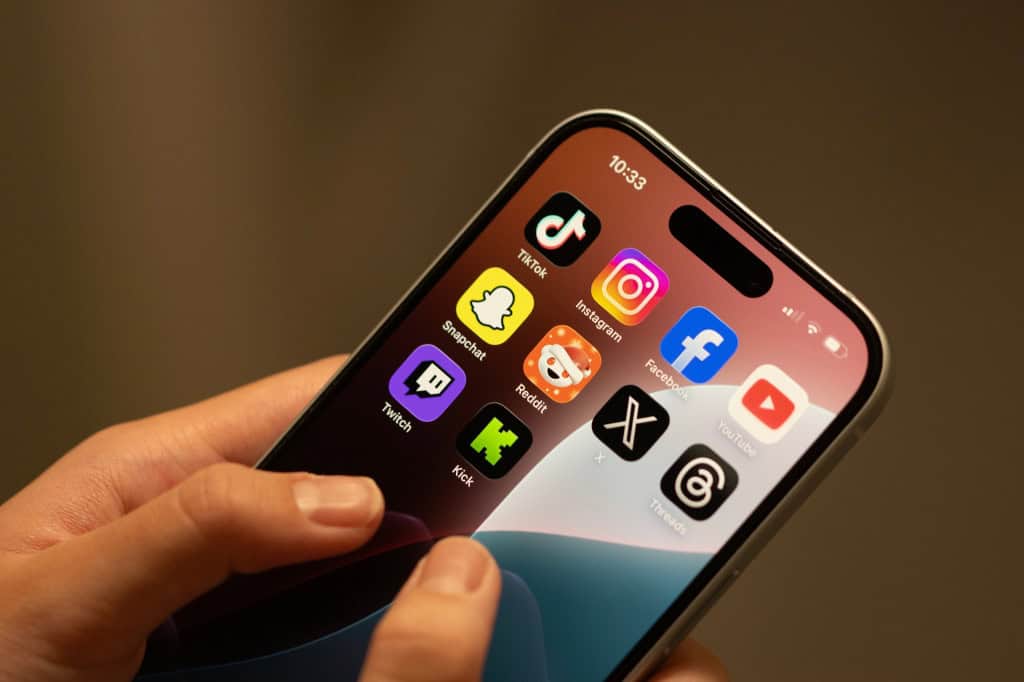 smartphone nas mãos de uma pessoa; na tela, ícones de redes sociais