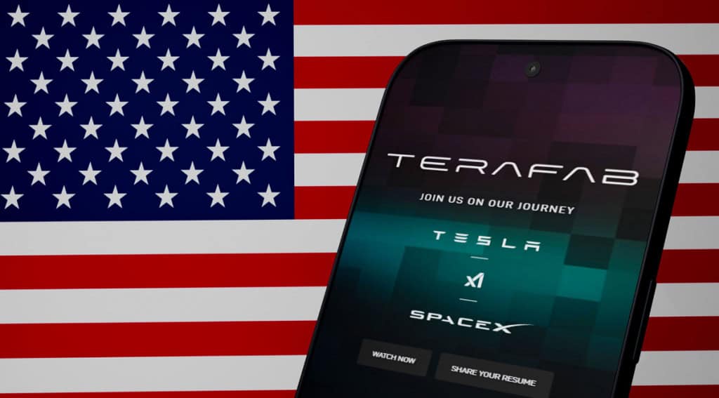 Logo da Terafab em um celular com os logos da Tesla e SpaceX, com a bandeira dos EUA de fundo