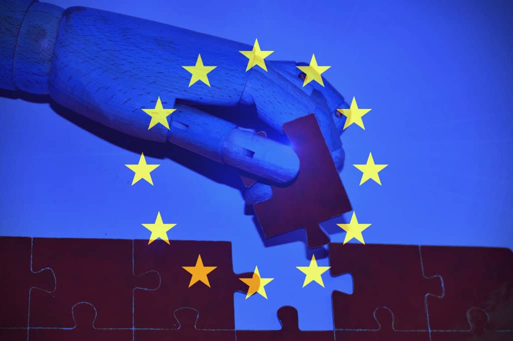 Ilustração mostra uma mão robótica encaixando uma peça de quebra-cabeça sobre um fundo com as estrelas da bandeira da União Europeia, simbolizando a regulamentação da inteligência artificial