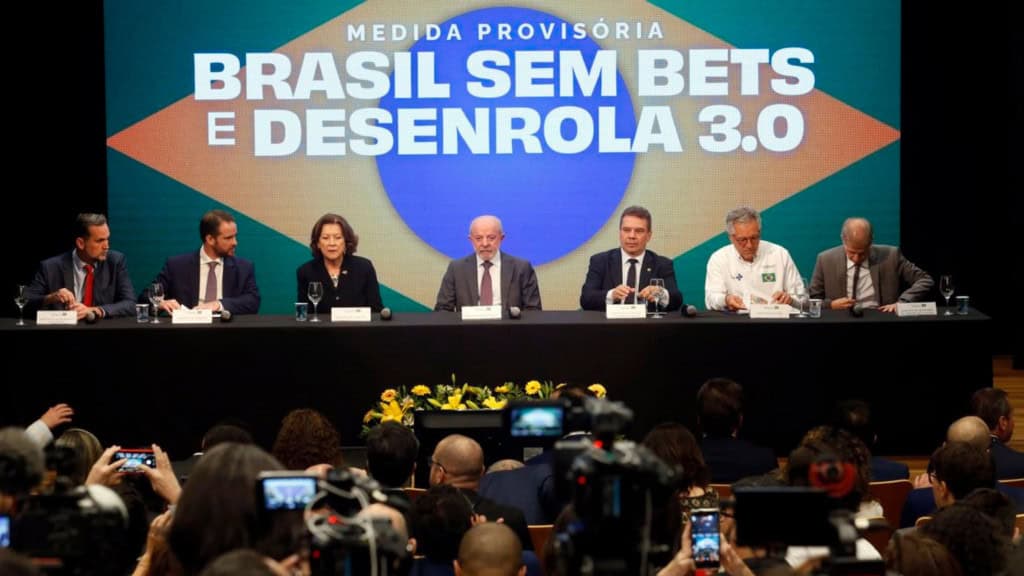 Lula e outros membros do governo em mesa durante evento que anunciou medida provisória proibindo bets no Brasil