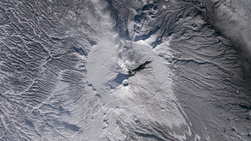 Vulcão Krasheninnikov coberto de neve e emitindo uma coluna de material em Kamchatka Vulcão Krasheninnikov coberto de neve e emitindo uma coluna de material em Kamchatka