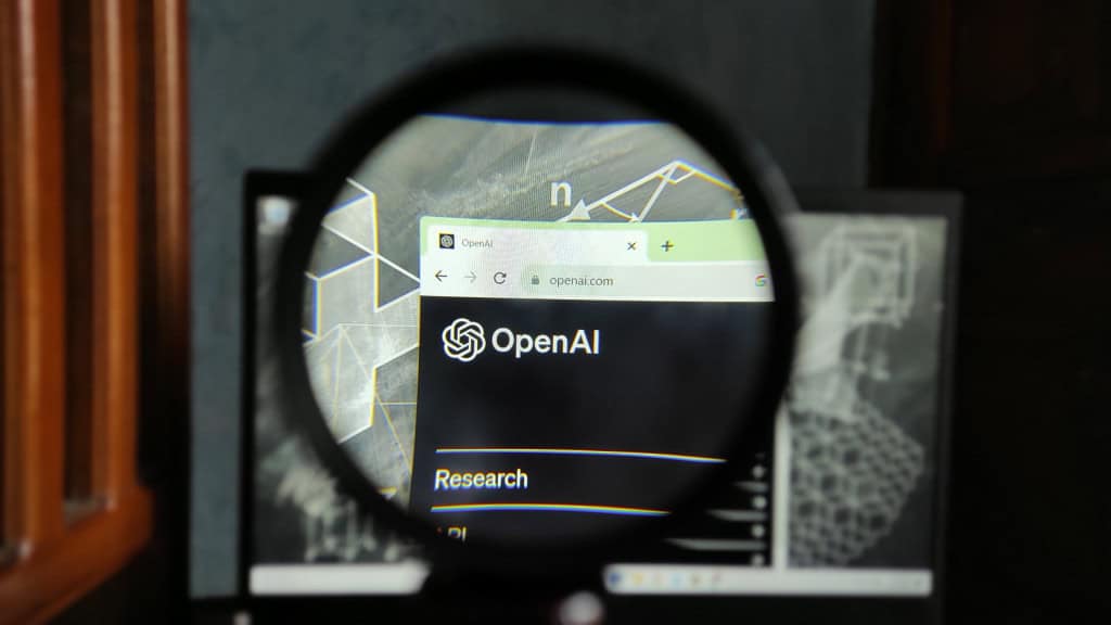 Logo da OpenAI em um navegador de internet observado por meio de uma lupa