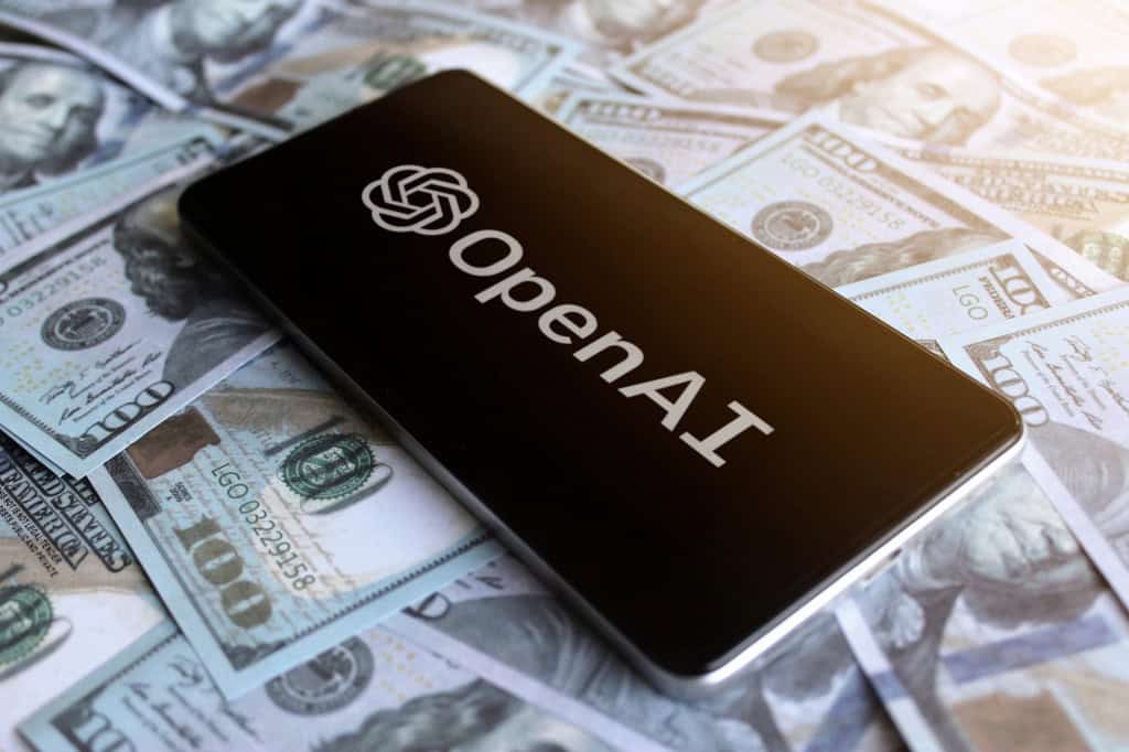 Logo da OpenAI em um smartphone que está em cima de várias notas de dólar
