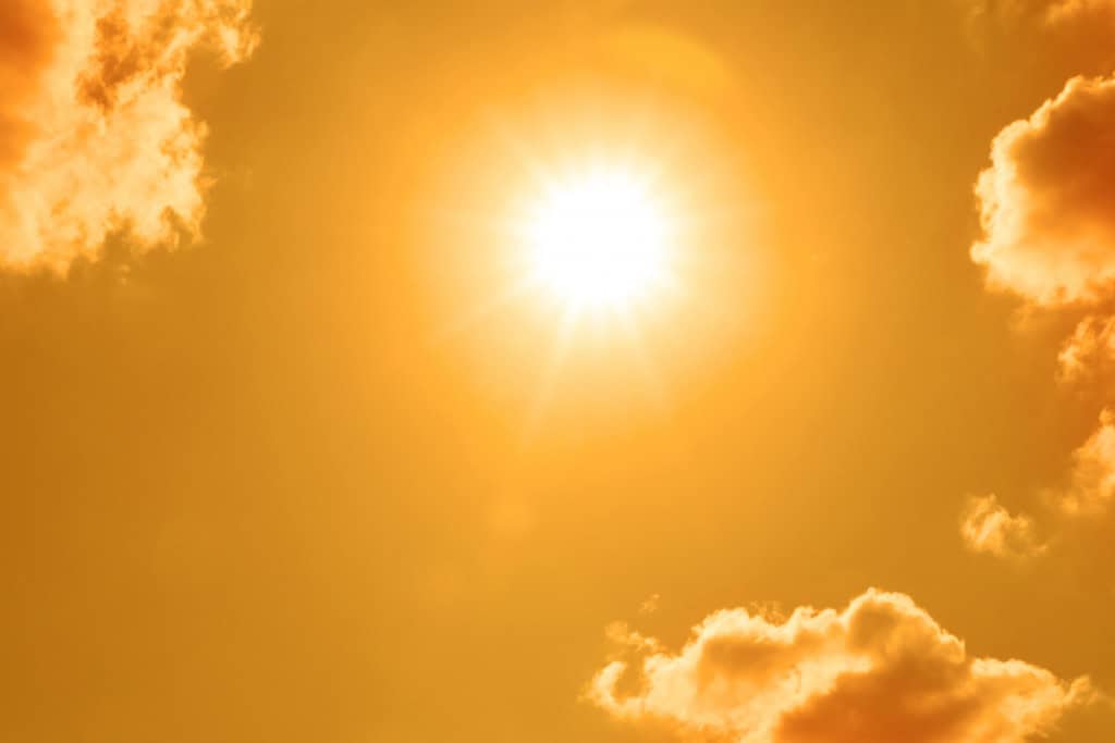 Sol e nuvens brilhantes no céu laranja durante o clima quente de verão
