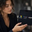 Mulher segurando um smartphone dobravel com os logos da Amazon, Microsoft e Alphabet na tela