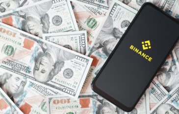 Logo da binance em um smartphone sobre uma pilha de dólares