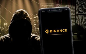 Logo da Binance em um smartphone com um hacker ao lado